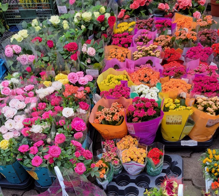 An assortment of fresh flowers arranged in colorful bouquets at a floral market. The display includes pink, white, and yellow roses, along with various small, brightly colored flowers such as daisy-li